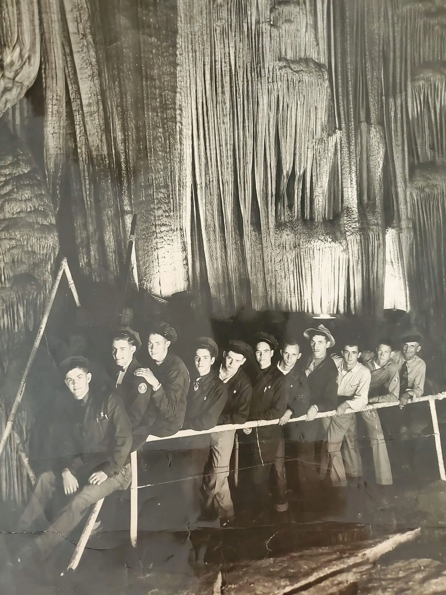 Black and white photo of young men posing by the stage curtain in Meramec Caverns